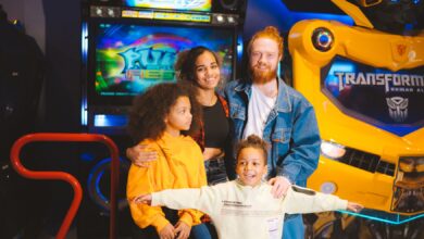 A cheerful family posing with arcade games and robots, capturing a vibrant amusement moment.