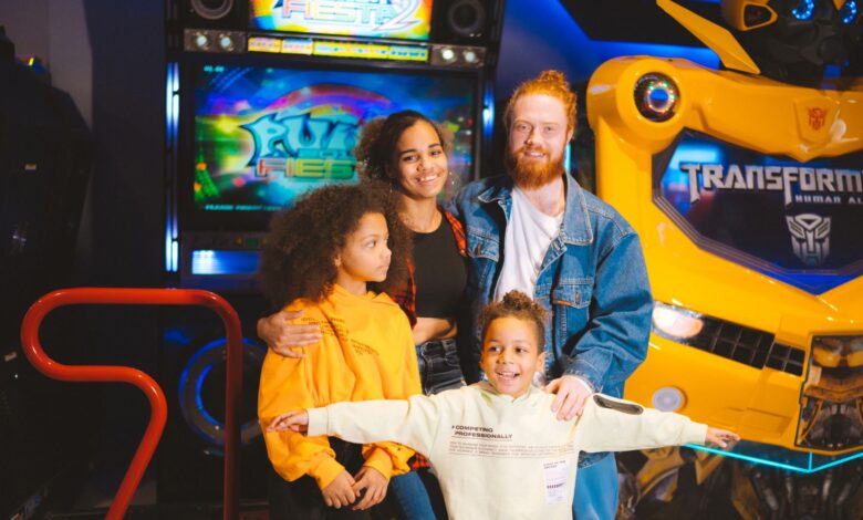A cheerful family posing with arcade games and robots, capturing a vibrant amusement moment.