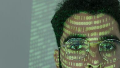 Close-up of a man with binary code projected on his face, symbolizing cybersecurity.