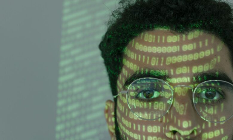 Close-up of a man with binary code projected on his face, symbolizing cybersecurity.