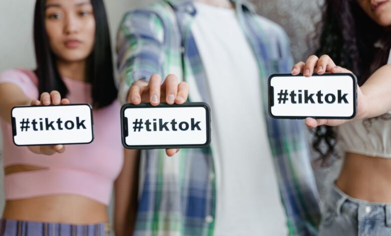 Young adults holding smartphones with TikTok hashtag, showcasing social media engagement.