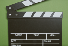 A classic film clapperboard on a green surface, essential for movie scenes.
