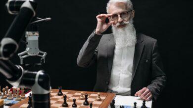 Senior man strategizing in a chess game against a robot, showcasing AI in leisure activities.