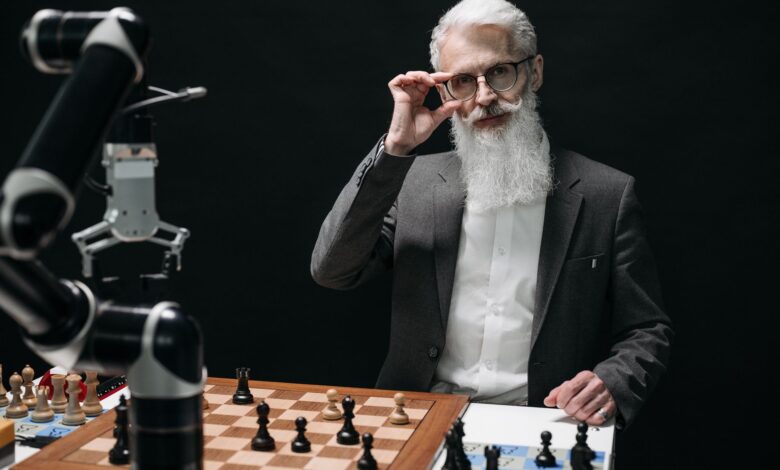 Senior man strategizing in a chess game against a robot, showcasing AI in leisure activities.