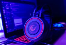 Close-up of gaming headset with neon lighting, placed next to a laptop. Perfect for tech and gaming themes.