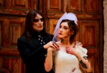 A couple in eerie Halloween wedding costumes posing with spooky makeup and props.