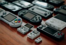 Collection of diverse retro handheld gaming consoles on a wooden surface, showcasing classic designs and nostalgia.