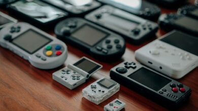 Collection of diverse retro handheld gaming consoles on a wooden surface, showcasing classic designs and nostalgia.