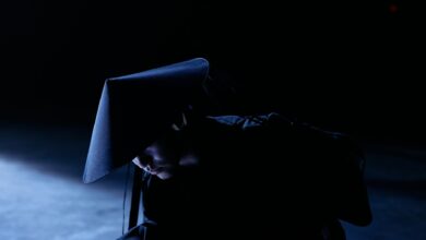 A mysterious figure in cosplay costume with a sakkat in a dark studio setting, conveying intrigue and concept.