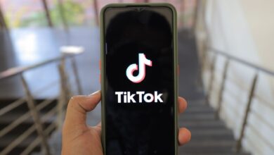 A close-up of a hand holding a smartphone displaying the TikTok app inside a modern building.