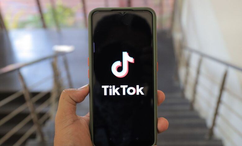 A close-up of a hand holding a smartphone displaying the TikTok app inside a modern building.