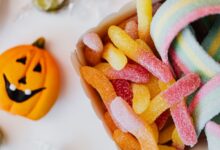 Colorful sour gummy candies and a jack-o'-lantern, perfect for Halloween celebration.