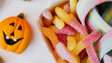 Colorful sour gummy candies and a jack-o'-lantern, perfect for Halloween celebration.