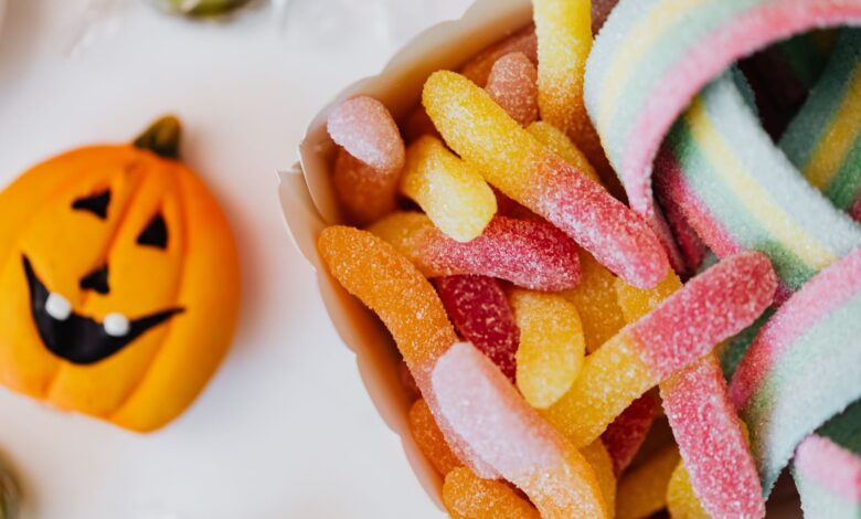 Colorful sour gummy candies and a jack-o'-lantern, perfect for Halloween celebration.