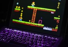 Close-up of a laptop displaying a retro video game with a neon-lit keyboard, capturing the nostalgic gaming experience.