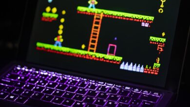 Close-up of a laptop displaying a retro video game with a neon-lit keyboard, capturing the nostalgic gaming experience.