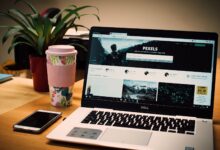 A tidy desk setting with a laptop showing a stock photo website and a smartphone.