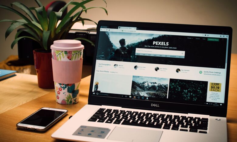 A tidy desk setting with a laptop showing a stock photo website and a smartphone.
