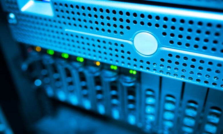 Focused view of a modern data server rack with blinking lights in a blue-lit environment.
