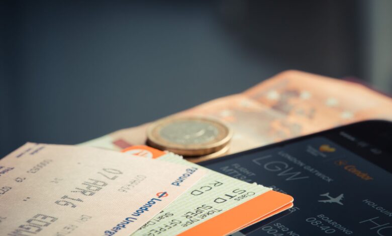 Airline ticket with euro coins and smartphone displaying flight details.