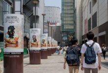 Bustling urban street in Chiyoda City, Tokyo with pedestrians and Final Fantasy ads.