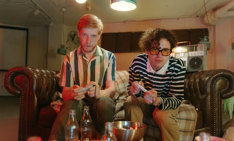 Two young men enjoying a video game night in a retro-inspired basement setting.