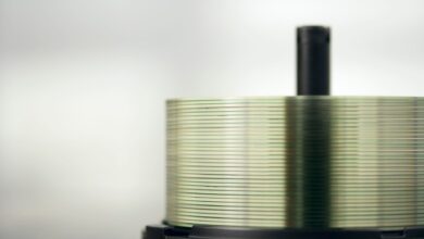 Detailed view of a stack of compact discs on a spindle, highlighting their reflective surfaces.