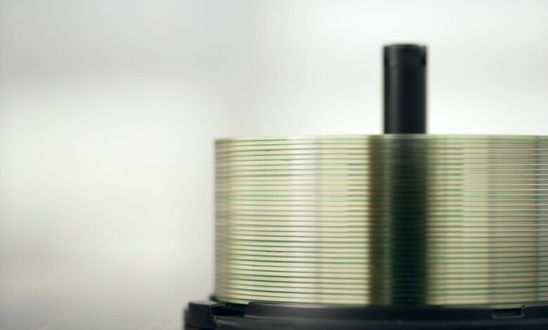 Detailed view of a stack of compact discs on a spindle, highlighting their reflective surfaces.