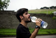 A young man drinks bottled water outside, staying hydrated and refreshed.