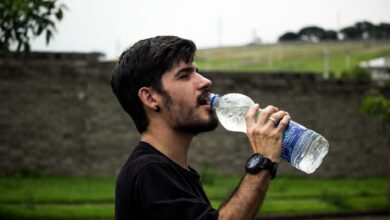 A young man drinks bottled water outside, staying hydrated and refreshed.