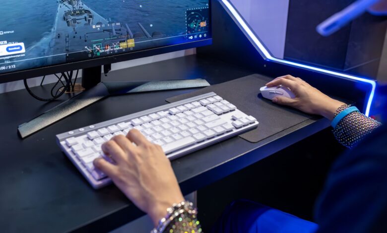 Close-up of a person gaming on a PC with a colorful setup and gaming accessories.