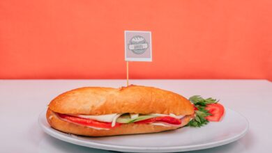 Fresh sub sandwich filled with veggies on a white plate against an orange background.