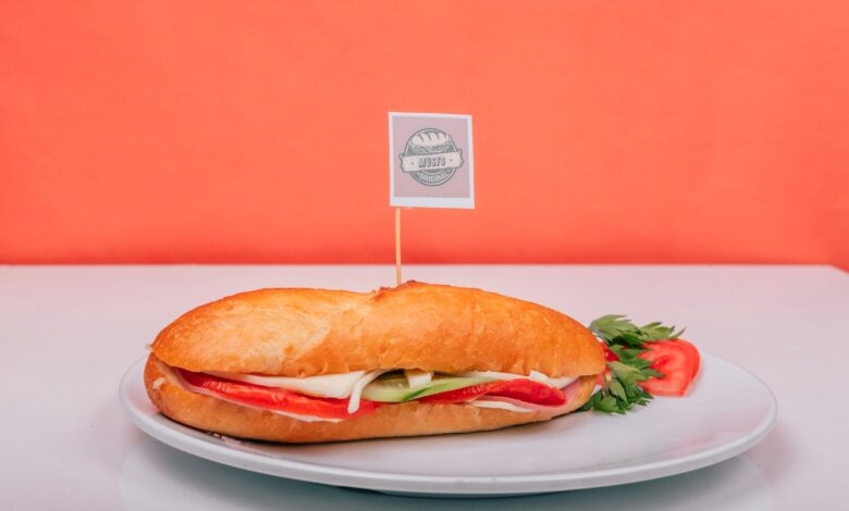 Fresh sub sandwich filled with veggies on a white plate against an orange background.