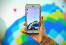 A person photographs a colorful hot air balloon festival using a smartphone, showcasing technology and travel.