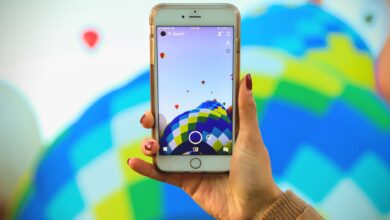 A person photographs a colorful hot air balloon festival using a smartphone, showcasing technology and travel.