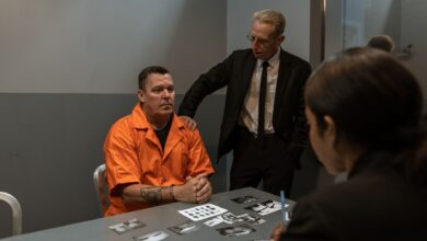 Prisoner in orange jumpsuit interviewed by detectives in a tense interrogation room scene.