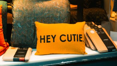 A vibrant yellow pillow with 'HEY CUTIE.' text displayed in a cozy shop setting in Freiburg, Germany.