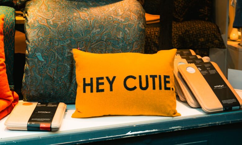 A vibrant yellow pillow with 'HEY CUTIE.' text displayed in a cozy shop setting in Freiburg, Germany.