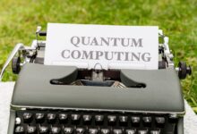 A typewriter with 'Quantum Computing' text outdoors on grass, blending old and new technologies.