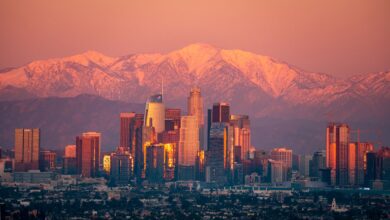 Stunning view of Los Angeles skyline with snow-capped mountains at sunset.