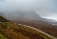 A winding road through a misty mountain landscape offering a serene and atmospheric view.