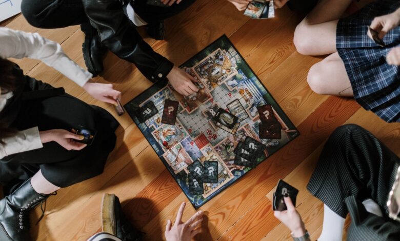 Aerial view of friends enjoying a board game on wooden floor.