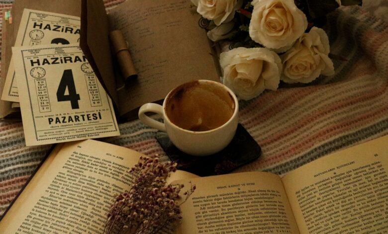 Aesthetic setup of coffee, books, and white roses on a cozy blanket.