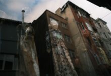 Artistic reflection of puppets through a window with urban buildings in the background.