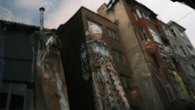 Artistic reflection of puppets through a window with urban buildings in the background.