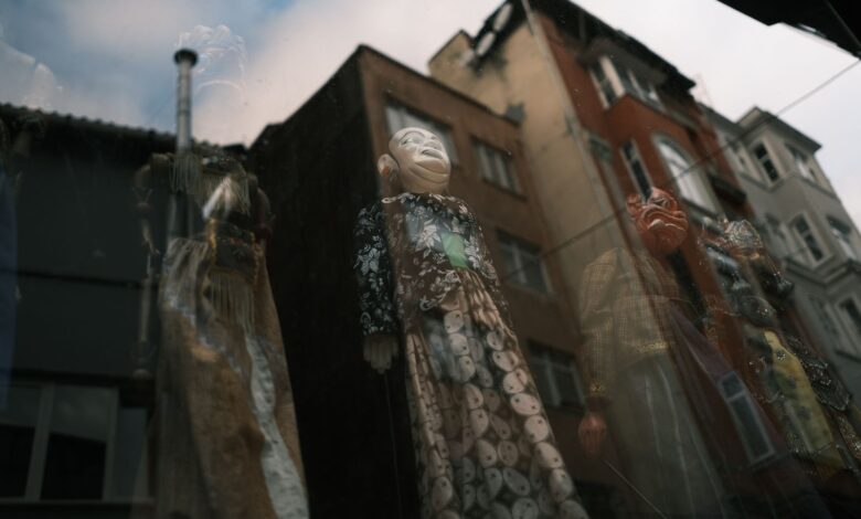 Artistic reflection of puppets through a window with urban buildings in the background.