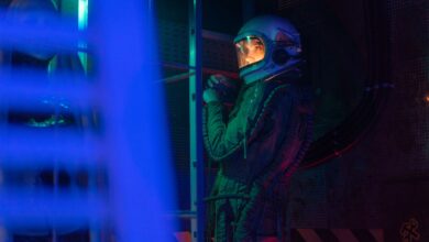 A female astronaut in a spacesuit stands in a neon-lit space shuttle, ready for interstellar exploration.