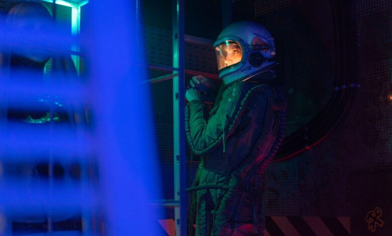 A female astronaut in a spacesuit stands in a neon-lit space shuttle, ready for interstellar exploration.