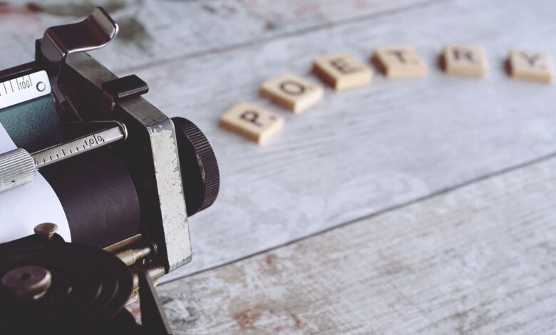 Close-up of a vintage typewriter with the word 'Poetry' spelled out on Scrabble tiles.