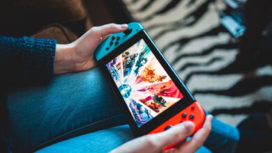 Person gaming on a handheld Nintendo Switch console with blurred background.